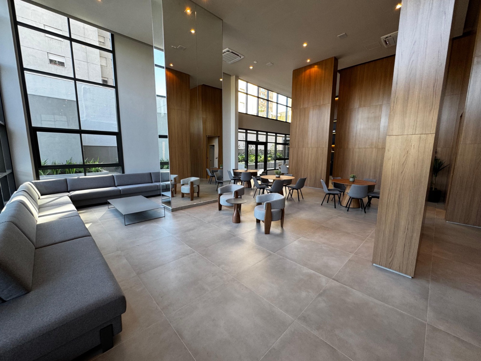 Lobby do condomínio com sofás, mesas e painéis de madeira