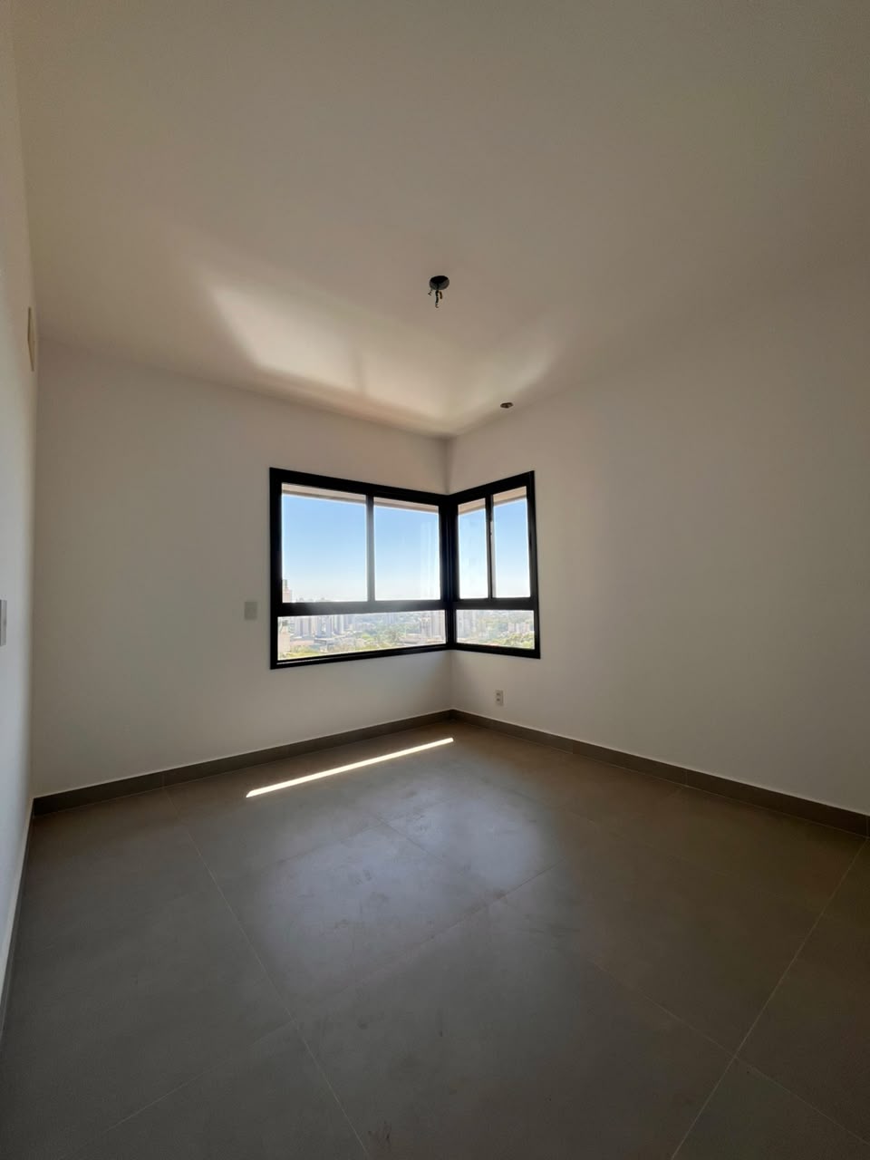 Suíte de canto do apartamento AP0437 com janelas em ângulo e vista da cidade