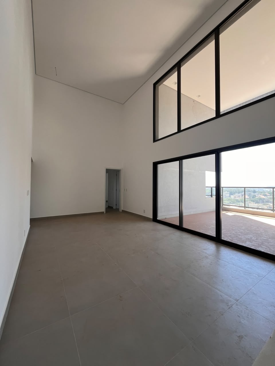 Living do apartamento AP0437 com pé-direito duplo e esquadrias pretas de piso ao teto