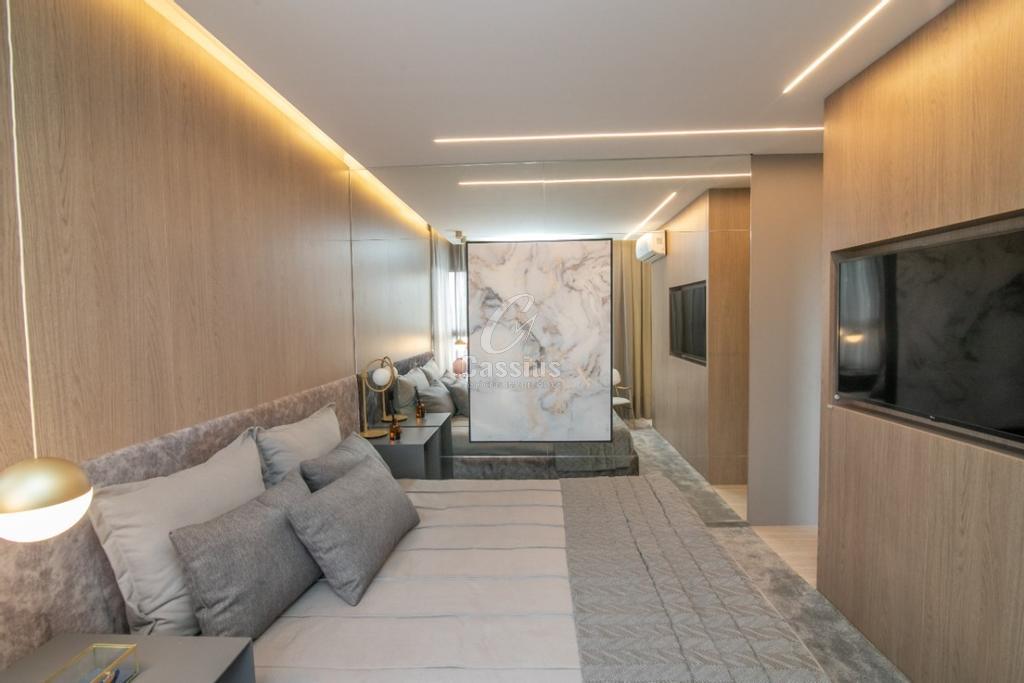 Suíte do apartamento decorado com painel de TV e marcenaria sob medida