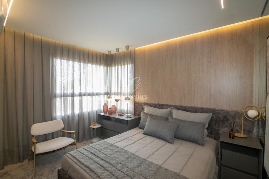 Suíte do apartamento decorado com cabeceira estofada e iluminação indireta