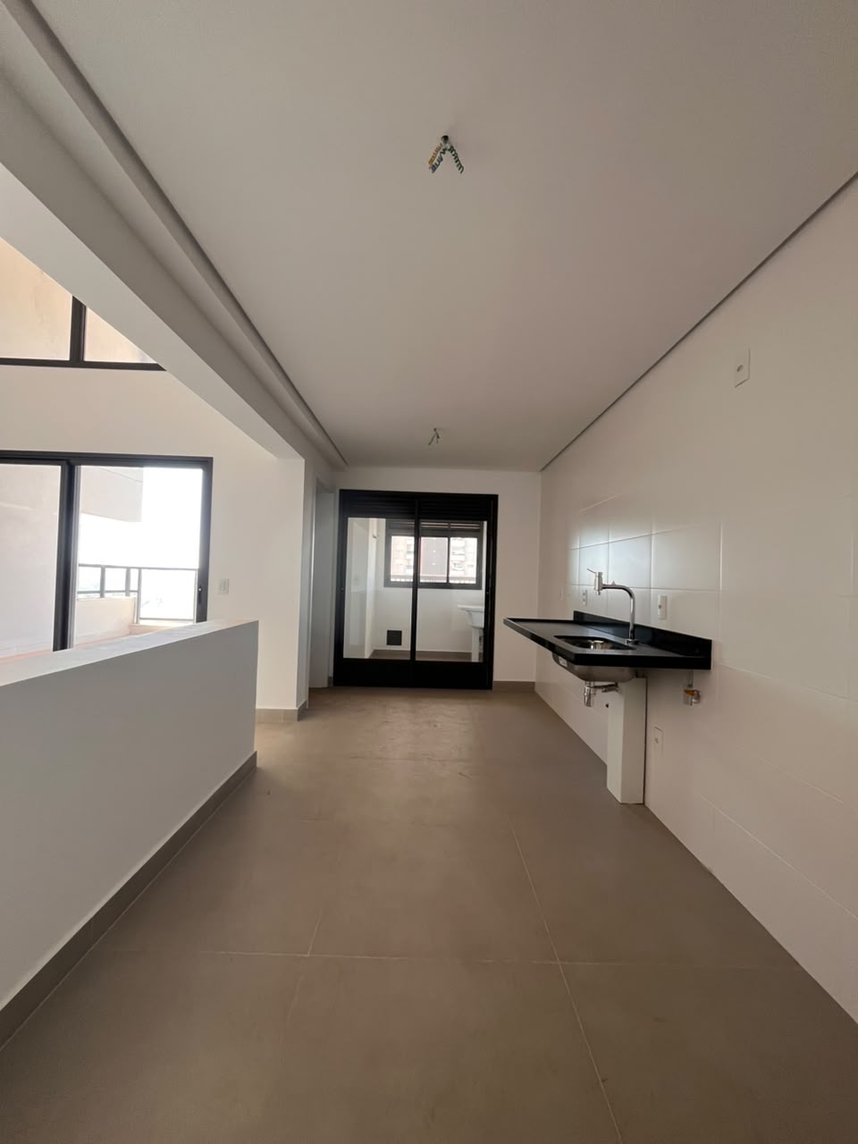 Cozinha do apartamento AP0437 com bancada preta e área de serviço envidraçada